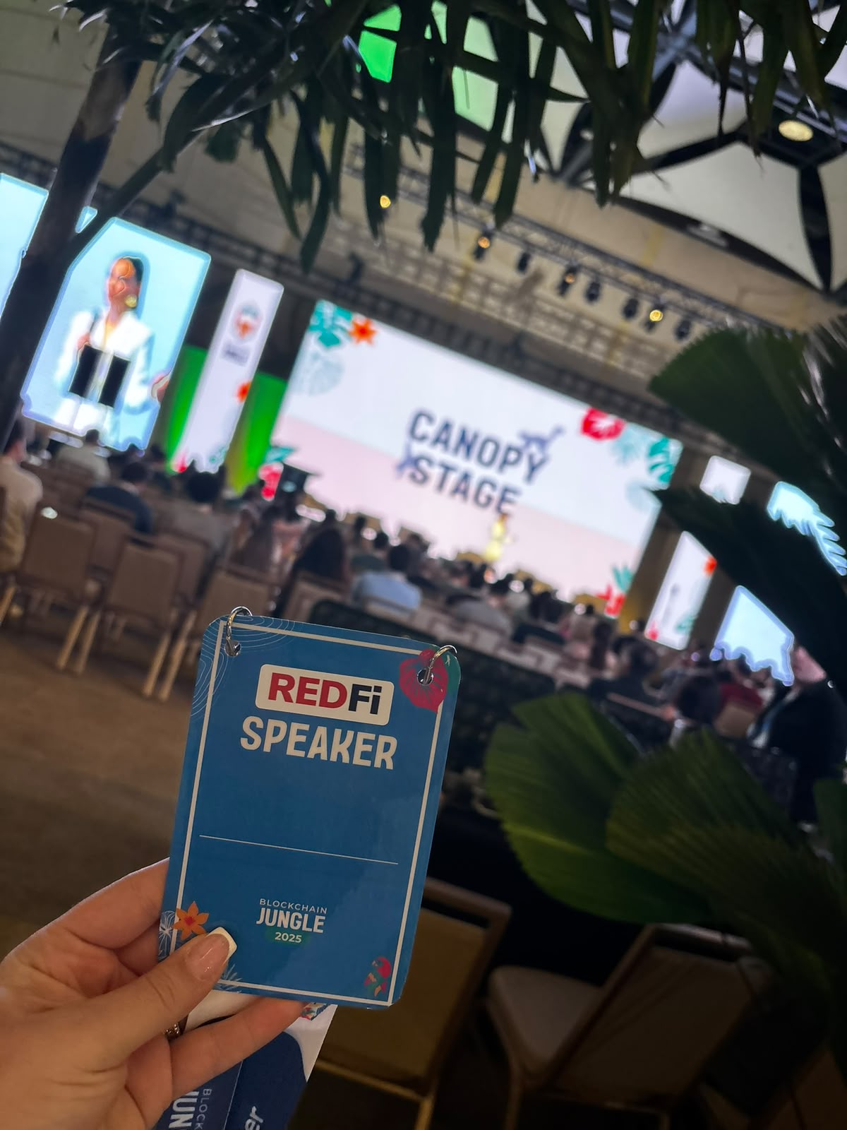 Credencial de speaker frente al escenario de Blockchain Jungle.